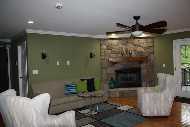 living area with a fireplace, crown molding, a barn door, ceiling fan, and wood finished floors