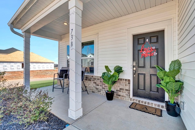 entrance to property featuring covered porch and brick siding