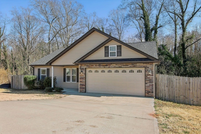 craftsman inspired home featuring a garage, stone siding, fence, and concrete driveway