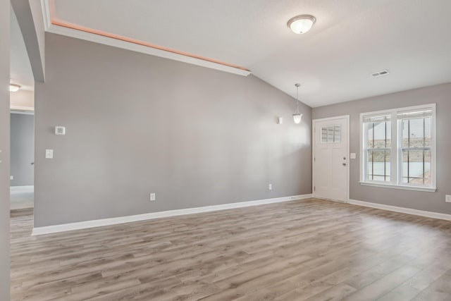 interior space with vaulted ceiling, light wood-type flooring, visible vents, and baseboards