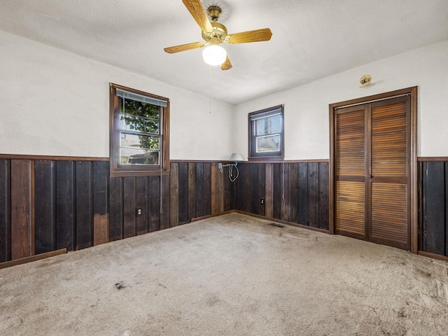 empty room featuring wainscoting, plenty of natural light, and wooden walls