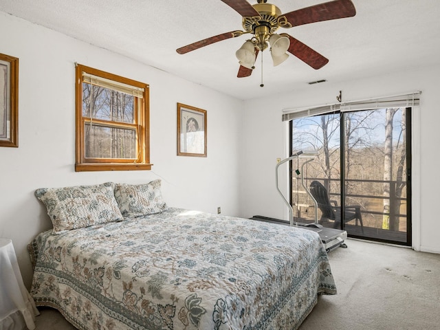 carpeted bedroom with access to exterior, ceiling fan, visible vents, and a textured ceiling