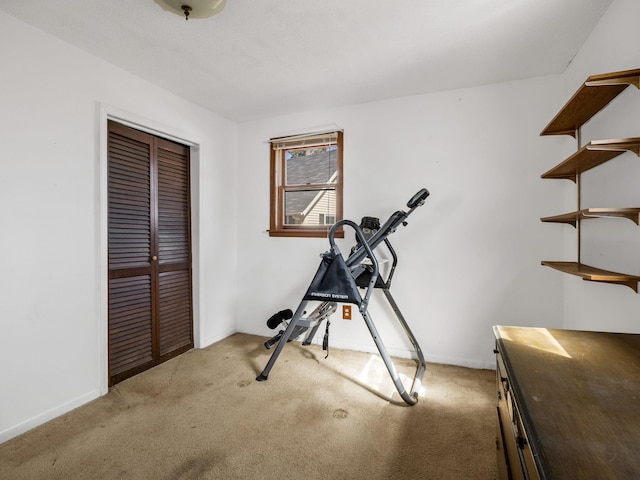 workout room featuring light carpet and baseboards