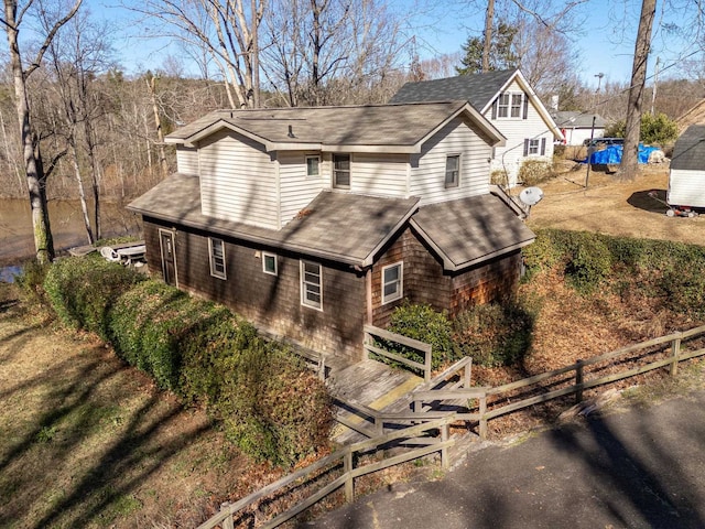 view of front of house featuring a shingled roof and fence