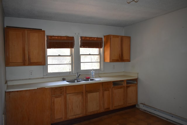 kitchen with a baseboard radiator, brown cabinets, a sink, and light countertops