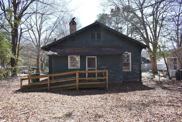 rear view of house featuring fence and a chimney