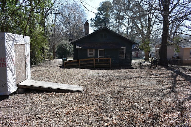 back of property with a chimney and fence