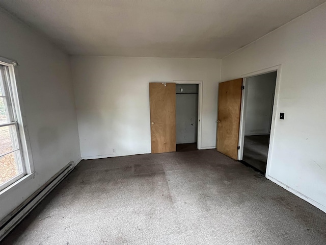 carpeted empty room featuring a baseboard radiator and a wealth of natural light