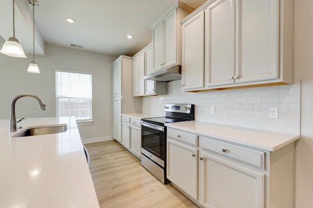 kitchen featuring stainless steel electric stove, visible vents, a sink, light wood-type flooring, and under cabinet range hood