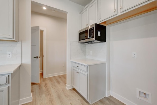 kitchen with light countertops, light wood finished floors, and stainless steel microwave