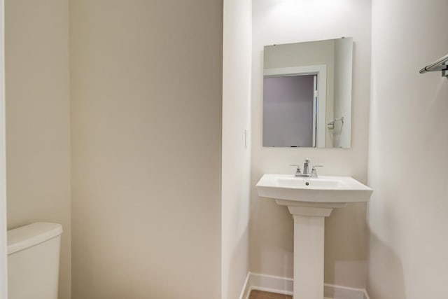 bathroom featuring a sink, toilet, and baseboards