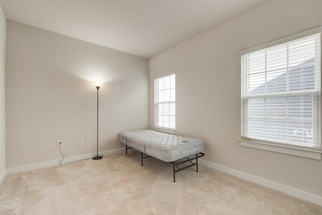 living area with baseboards and light colored carpet