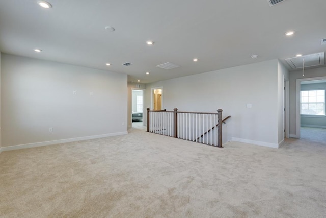 spare room with attic access, recessed lighting, light colored carpet, and baseboards