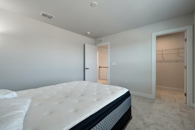 bedroom with baseboards, a spacious closet, visible vents, and light colored carpet