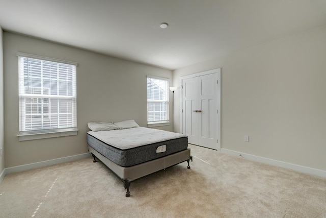 carpeted bedroom featuring a closet and baseboards