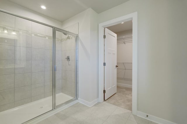 bathroom featuring a stall shower, tile patterned flooring, a spacious closet, and baseboards