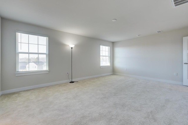 spare room featuring baseboards, visible vents, and light colored carpet