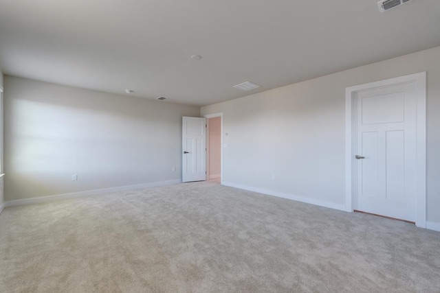 empty room featuring light carpet, visible vents, and baseboards