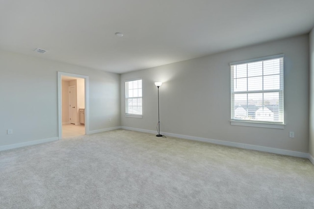 unfurnished room with visible vents, baseboards, and light colored carpet