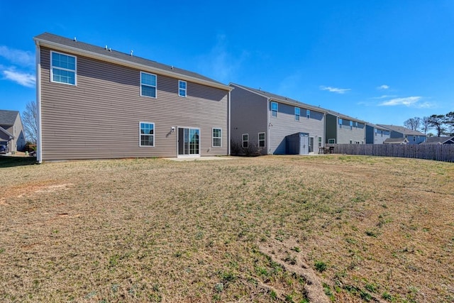 rear view of house with fence and a lawn