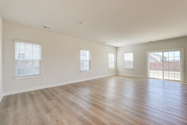 unfurnished room with light wood finished floors, visible vents, and baseboards