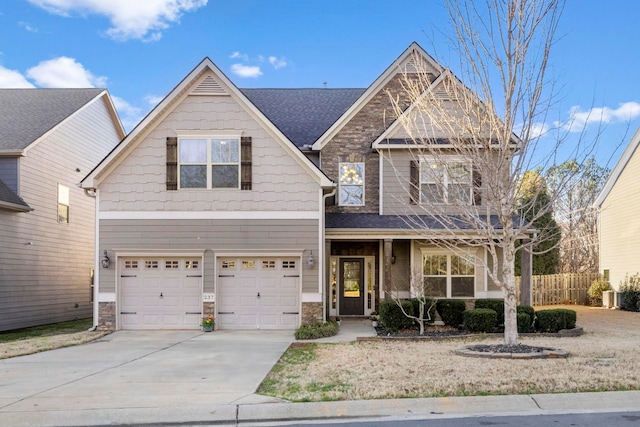 craftsman-style house with driveway, a garage, a shingled roof, stone siding, and fence