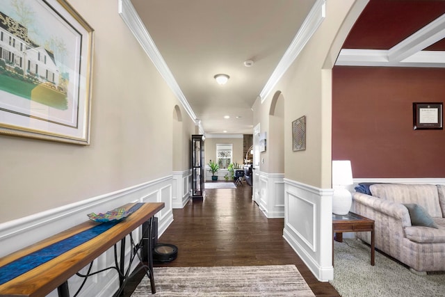 hall featuring arched walkways, a decorative wall, wood finished floors, and wainscoting