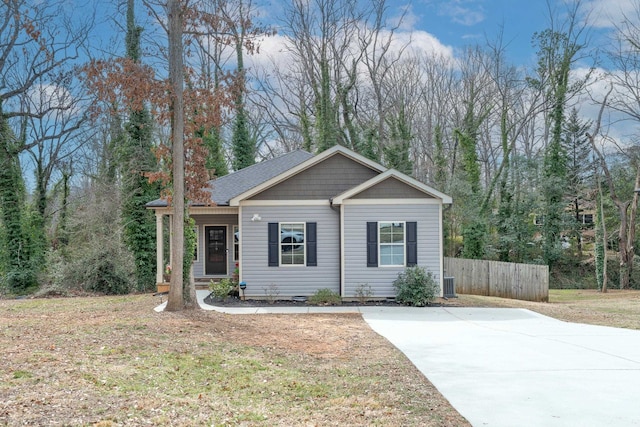 view of front of house with central AC unit, a front yard, and fence