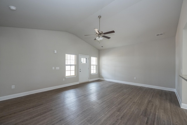 spare room featuring visible vents, dark wood-type flooring, vaulted ceiling, ceiling fan, and baseboards