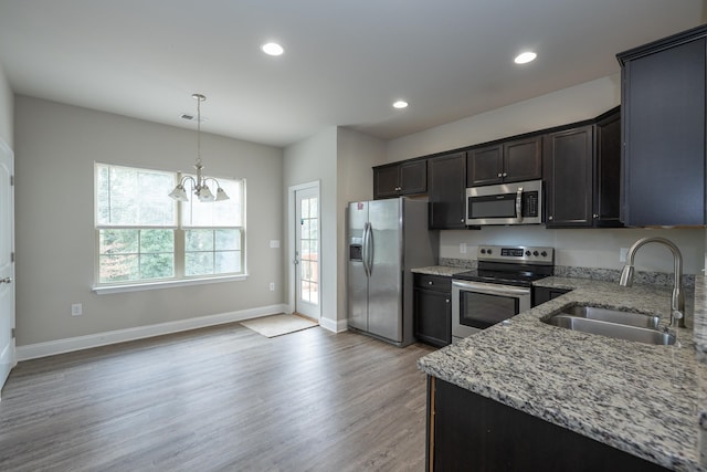 kitchen with light wood finished floors, visible vents, light stone counters, stainless steel appliances, and a sink