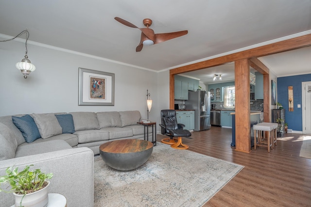 living room featuring ceiling fan, baseboards, dark wood finished floors, and crown molding