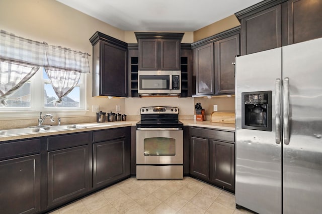 kitchen featuring light tile patterned floors, a sink, light countertops, appliances with stainless steel finishes, and dark brown cabinets