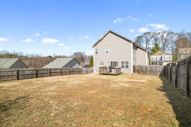 back of property with a fenced backyard, a yard, and a deck