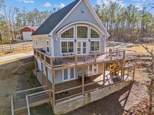 back of house featuring a deck, a detached garage, driveway, french doors, and roof with shingles