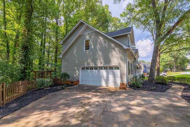 view of home's exterior with crawl space, driveway, a garage, and fence