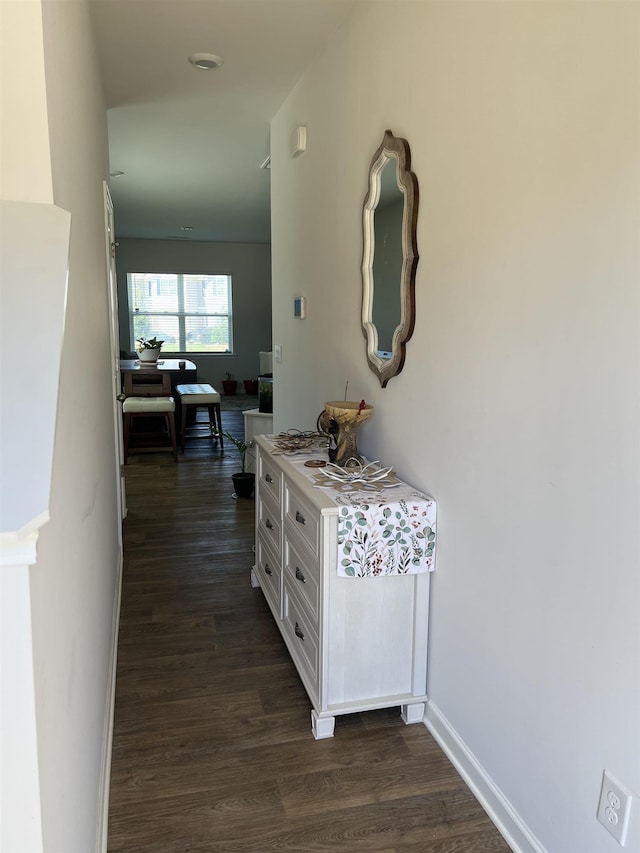 corridor featuring baseboards and dark wood-style flooring