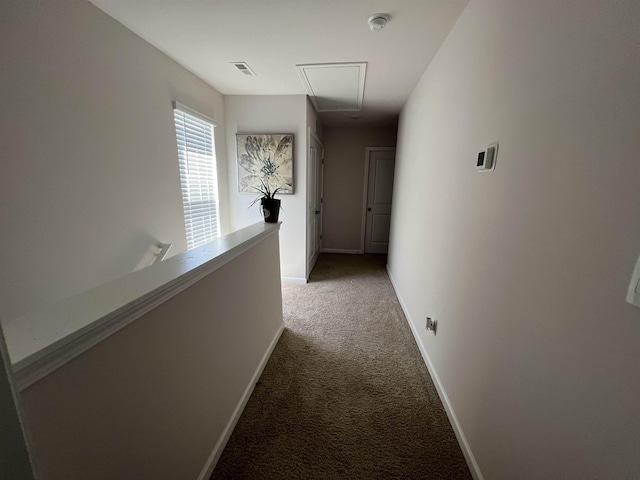 corridor with visible vents, baseboards, light colored carpet, and attic access