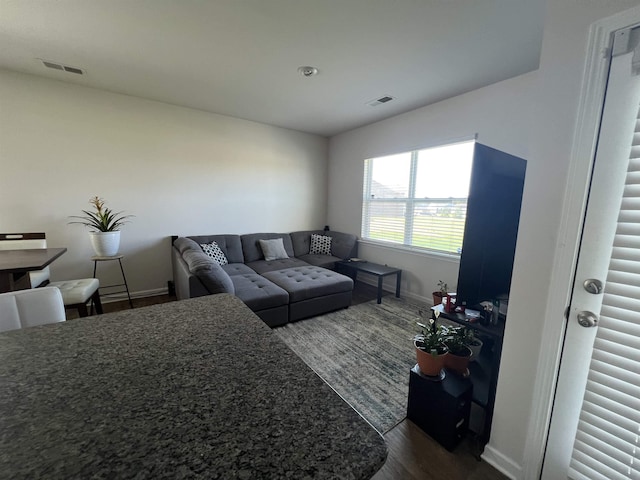 living room featuring visible vents, dark wood-type flooring, and baseboards