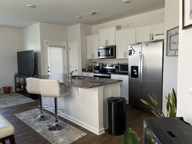 kitchen featuring visible vents, a center island with sink, white cabinets, stainless steel appliances, and a sink