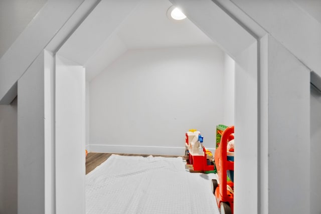 recreation room with vaulted ceiling, baseboards, and wood finished floors