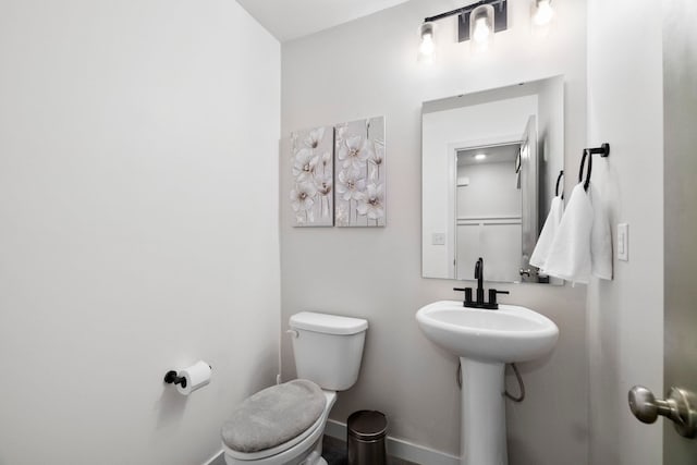 half bath with baseboards and toilet