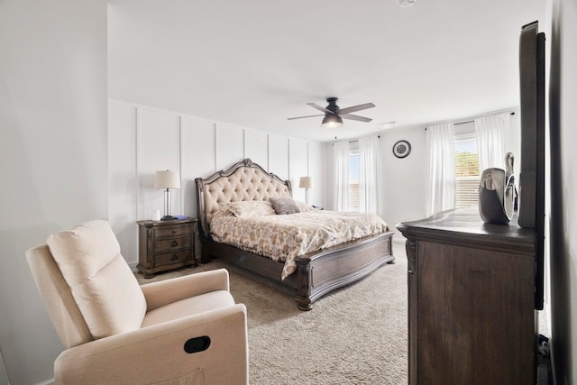 carpeted bedroom featuring a ceiling fan and a decorative wall