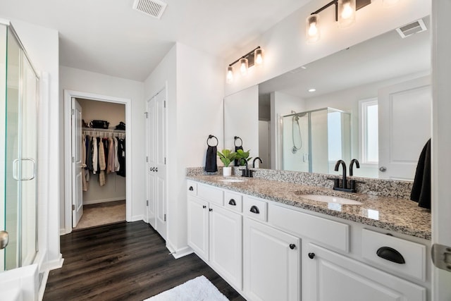 full bath featuring a stall shower, visible vents, a sink, and wood finished floors