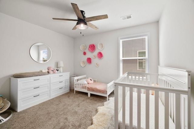 bedroom with light carpet, multiple windows, a nursery area, and visible vents