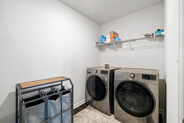 laundry room featuring laundry area, wood finished floors, washing machine and clothes dryer, and baseboards