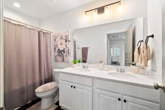 full bathroom with visible vents, a sink, toilet, and double vanity