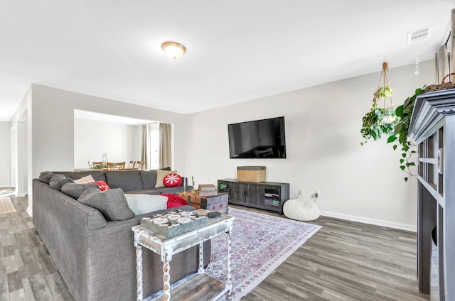 living room with visible vents, baseboards, and wood finished floors