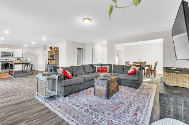 living area with baseboards, light wood finished floors, and recessed lighting