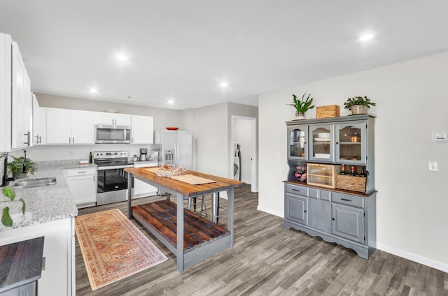 kitchen with light stone counters, a sink, white cabinets, light wood-style floors, and appliances with stainless steel finishes