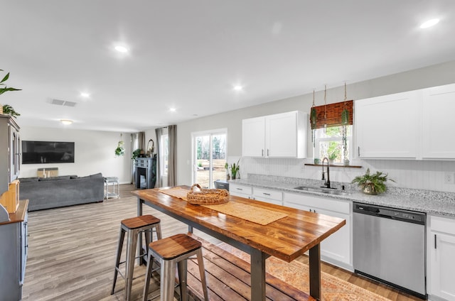 kitchen featuring visible vents, stainless steel dishwasher, a healthy amount of sunlight, a sink, and white cabinetry